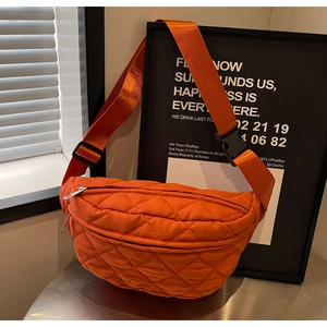 Detailed macro shot of orange quilted nylon belt bag with adjustable strap and zip pocket