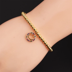Close-up of a gold-plated beaded bracelet with a colorful zircon smiley face pendant