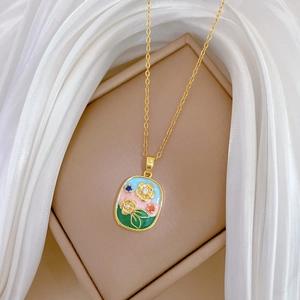 Monet Garden style gold titanium necklace with colorful enamel floral pendant on white silk