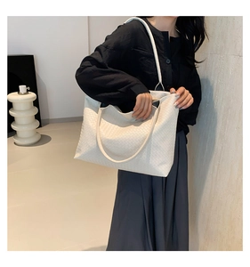 Detail of white woven leather texture on a large capacity tote bag with shoulder strap