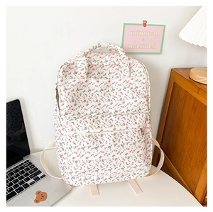 Detailed view of floral canvas backpack in a warm wooden desk and minimalist room setting