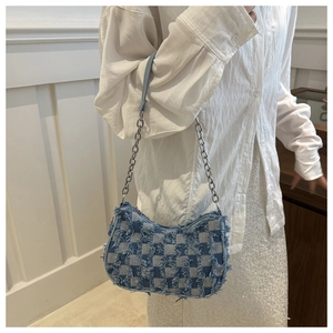Detail of blue denim plaid underarm bag with metal chain strap and zip closure