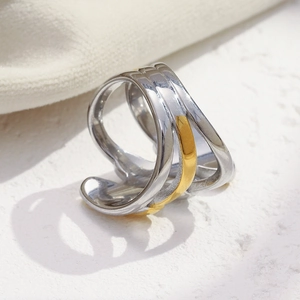 Three-layer crisscross gold and silver plated stainless steel ring on a stone surface