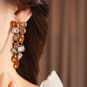 Close-up of vintage drop earrings with amber and champagne crystals on gold alloy