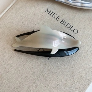Detailed close-up of a pearlescent dolphin hair clip with a sparkling star rhinestone