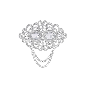 Elegant silver vintage brooch with crystals and hanging chains on white background