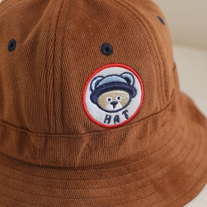 Détail d'un chapeau bob en velours côtelé marron avec un patch brodé d'ours mignon