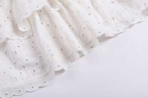 Gros plan sur la broderie florale en dentelle blanche avec détails ajourés délicats