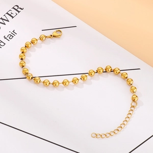 Detalle de pulsera de cuentas doradas pulidas con cierre de mosquetón y cadena ajustable