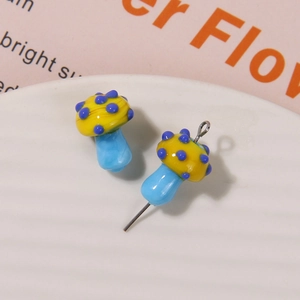 Macro detail of cute yellow and blue polka dot glass mushroom charms for DIY jewelry making