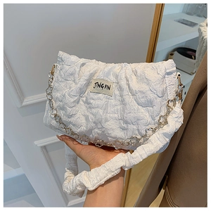 Detail of white pleated handbag featuring a golden flower chain and JING PIN fabric tag