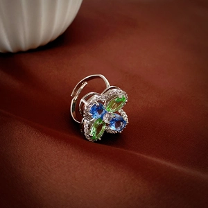 Macro shot of silver ring with green and blue marquise stones in floral design
