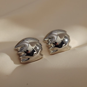 Abstract silver wavy earrings with liquid metal texture on beige silk background