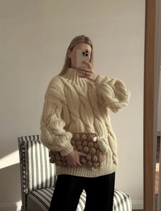Detail of cream cable knit sweater with puff sleeves and matching textured clutch bag