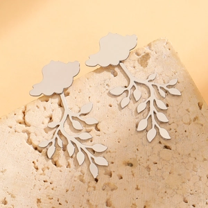 Macro view of silver leaf pendant earrings on a stone base with polished mirror finish
