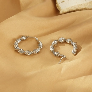 Macro shot of silver twisted hoop earrings with sparkling rhinestones on golden satin