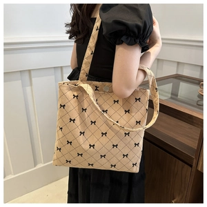 Dettaglio della borsa tote in velluto beige con motivo a rombi e fiocchi sulla spalla