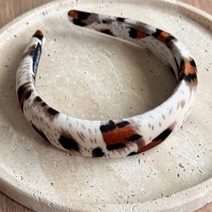Close-up of handmade wide velvet leopard print headband with a hand made label