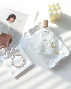 Detail of white ceramic tray with embossed bow design showcasing elegant gold jewelry
