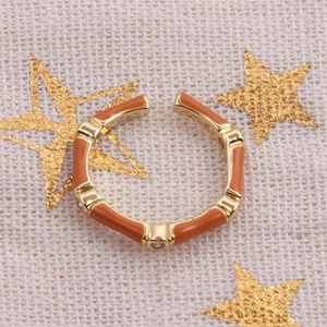Macro shot of orange enamel bamboo ring with gold accents and zircon inlay detail