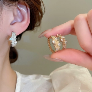 Detail of textured geometric hoop earrings with zircon stones in gold and silver finish