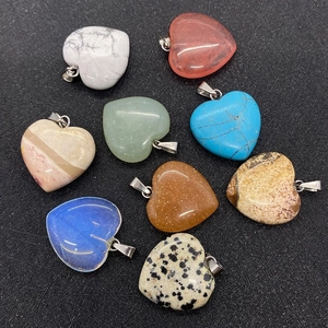 Collection of heart-shaped natural stone pendants in various colors on black background