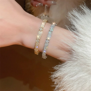Close-up of sparkling zircon flower bangles in gold and silver on a fur sleeve