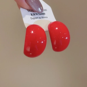 Detailed view of glossy red teardrop acrylic stud earrings with silver needle on display card