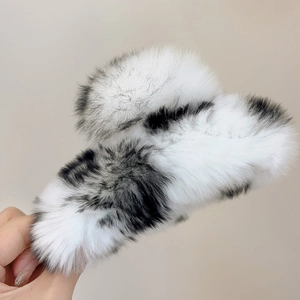 Macro shot of large plush shark hair clip with black and white cow print fur texture
