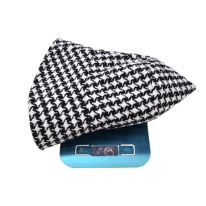 Detailed view of black and white houndstooth bucket hat weighing 125g on a scale