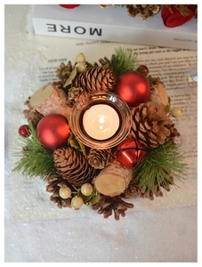 Detail view of a Christmas pine cone wreath candle holder with natural wood and glass