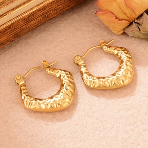 Gros plan détaillé de boucles d'oreilles dorées en U avec texture martelée et vintage