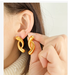 Macro view of geometric twisted link gold earrings with polished 18k finish