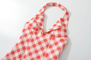 Detail of red and white plaid halter dress featuring V-neckline and decorative lace trim