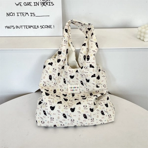 Dettaglio della borsa tote in tela bianco sporco con stampe di gatti ed etichetta tessuta