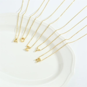 Minimalist gold letter necklace set with A, C, Z, Y, R pendants on white ceramic plate