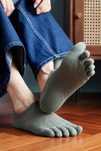 Detail of grey-green toe socks with breathable mesh texture on wood floor background