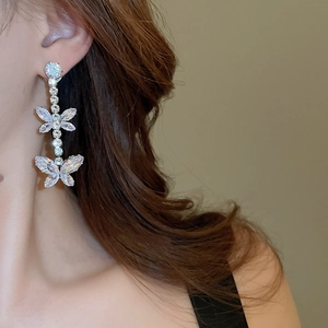 Close-up of dangling silver butterfly earrings with sparkling cubic zirconia stones
