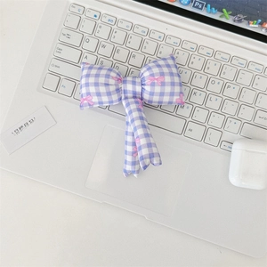 Close-up of a purple checkered bow pendant with pink floral prints on a laptop