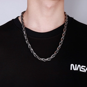 Collier chaîne serpent en acier titane rétro porté par un mannequin homme sur mur clair