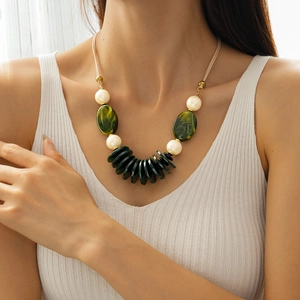 Detail of beaded necklace with green acrylic pendants and white pearls on a model