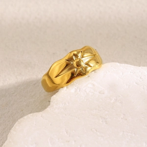 Macro detail of 18K gold plated stainless steel star ring on a textured white stone base