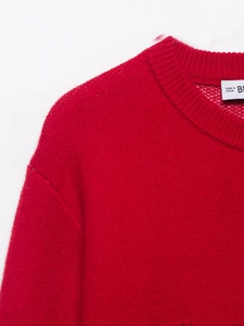 Gros plan détaillé de l'encolure ronde et de la texture du tricot du pull rouge