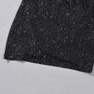 Detail of black mini skirt featuring white speckled star print and overlocked hemline