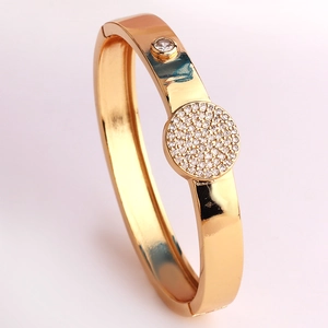 Dettaglio del bracciale rigido dorato con brillanti zirconi rotondi incastonati micro-pave