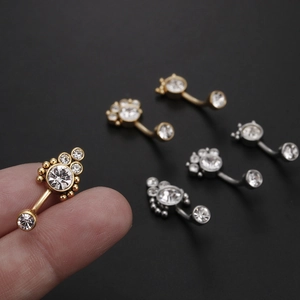 Piercings de nombril en zircone dorée, argentée et or rose sur un fond noir chic