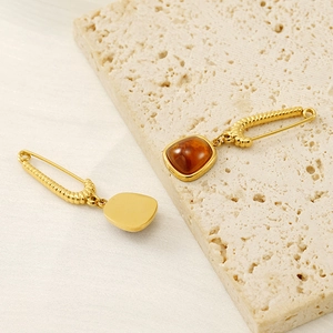 Detail of safety pin earrings with textured gold plating and amber stone drops