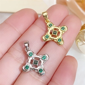 Detailed macro view of gold and silver four-leaf clover pendants with green zircons