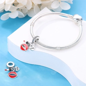 Detail of silver heart charm bracelet with red lipstick and kiss pendants