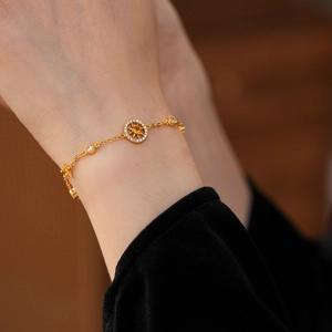 Detail of gold compass bracelet with yellow zircon and sunburst pattern on wrist